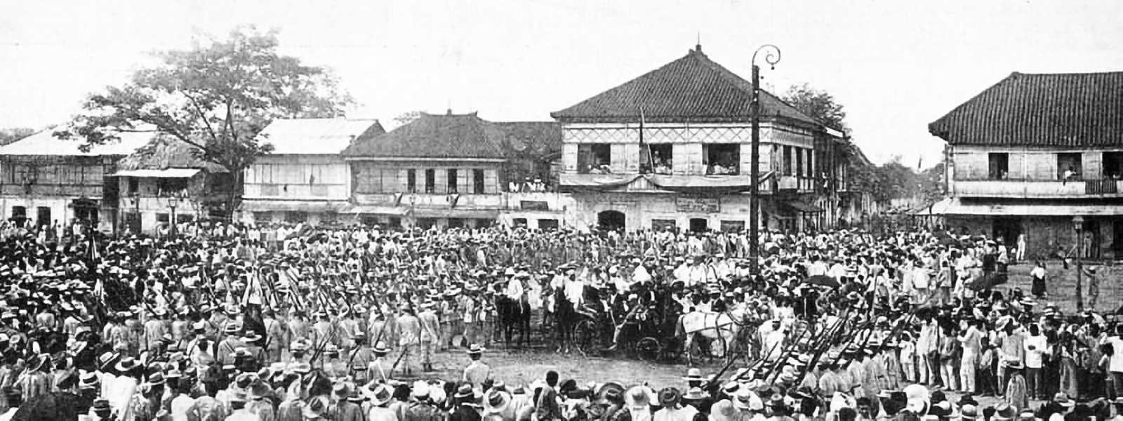 Black and white photo of many people gathered in a town center